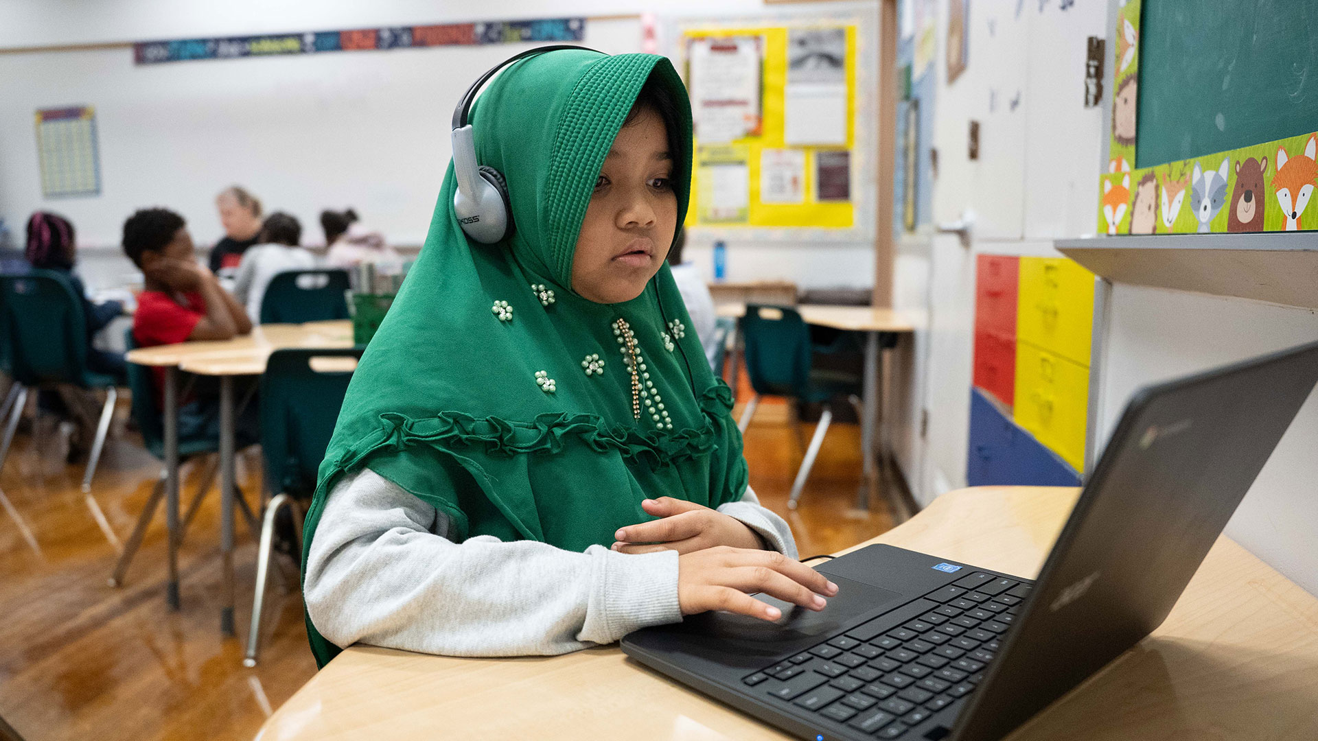 A young child in a classroom using a computer.
