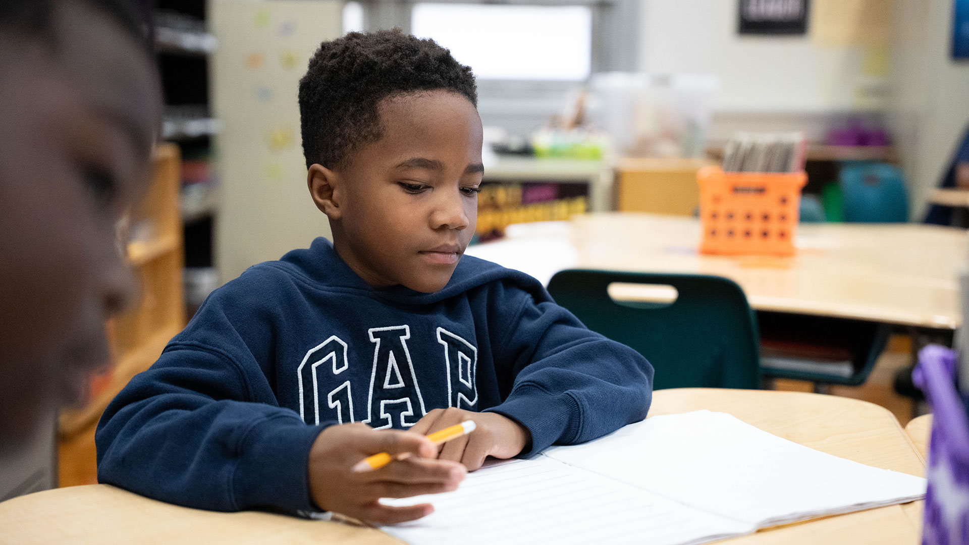 A child in a classroom preparing to write.