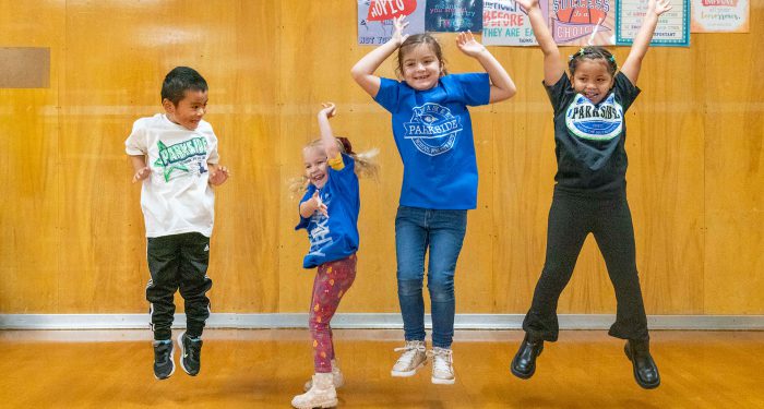Four children in a line, jumping.