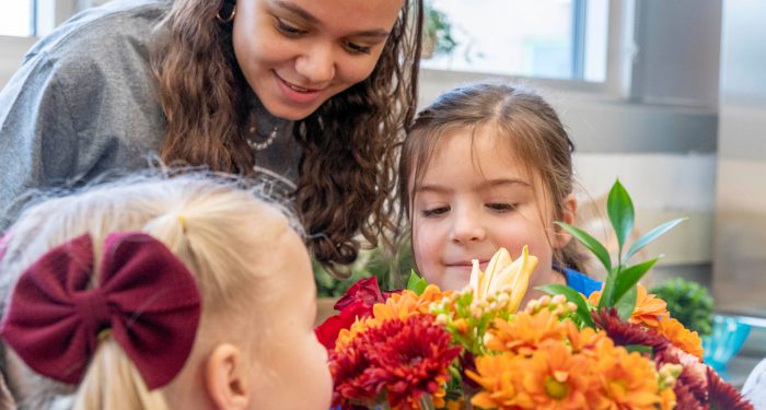 Close-up of children smelling flowers.