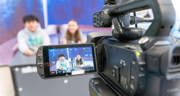 A camera screen captures video of student announcers.