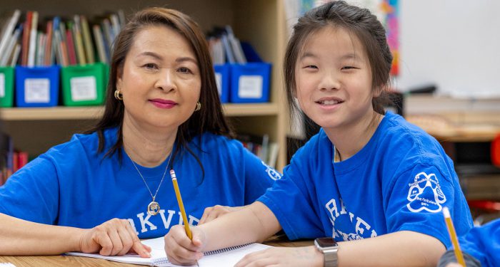 A teacher and her student smiling.