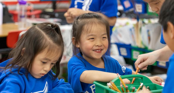 Young children picking crayons from a bin.
