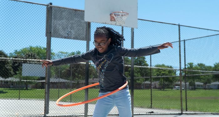 A girl on a playground hula-hooping.