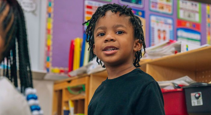 A young child in a colorful classroom.