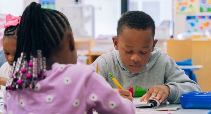 Young students in a classroom writing in their workbooks.