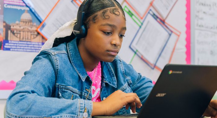 A student in a classroom using a laptop.
