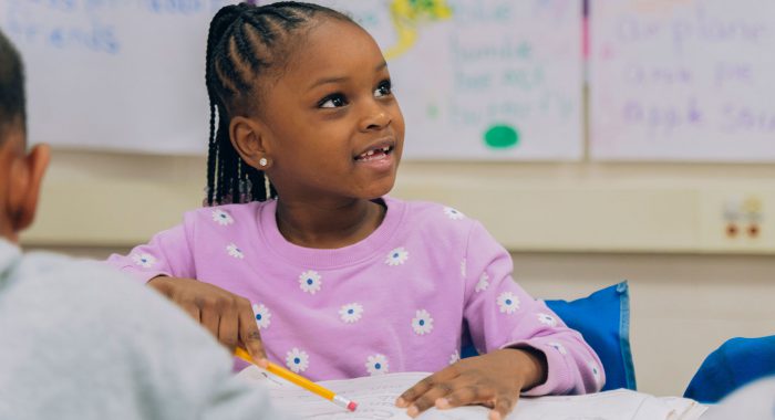 A young child in a classroom smiling.