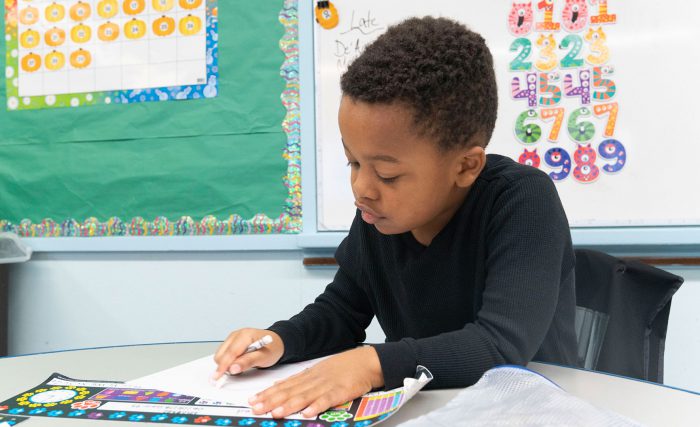A young child in a classroom coloring.