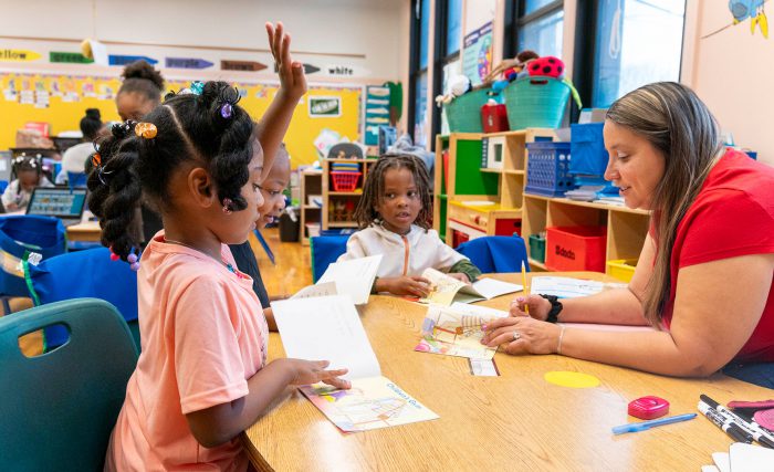 A teacher works with her young students on reading.
