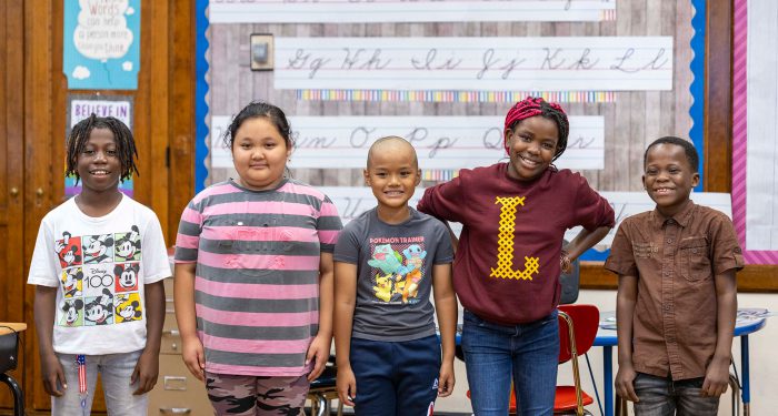 Five students stand next to eachother in a line.