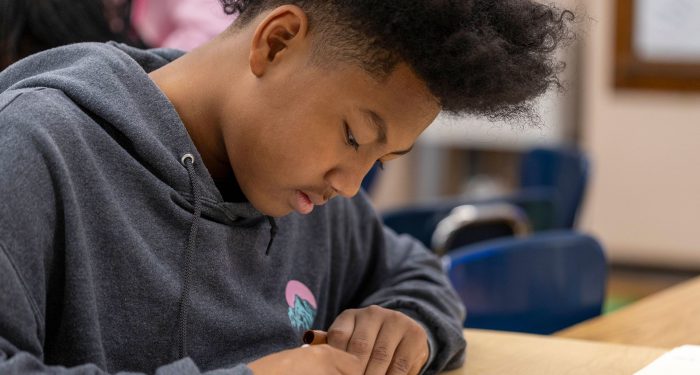 A boy at a table writing.
