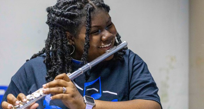 A student smiles as she prepares to play the flute.