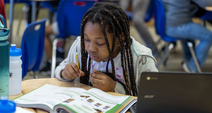 A girl looks in a workbook.