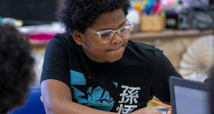 A student with glasses concentrates on school work.