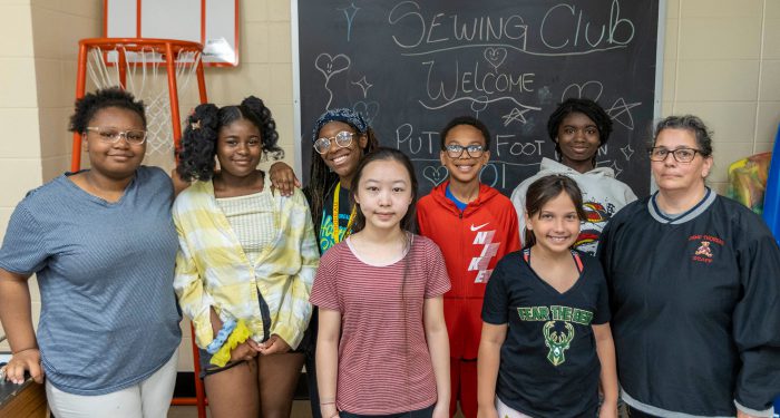 Members of the sewing club pose in a classroom.