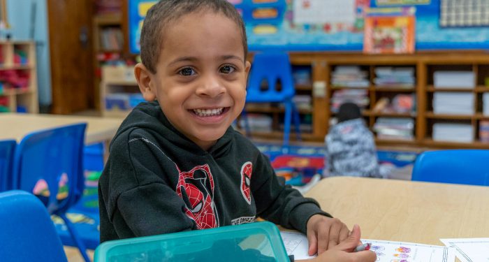 A young student smiles at the camera.