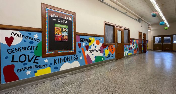 A school hallway with the painted words: Perseverance, generosity, love, empowerment, kindness, bravery, and compassion.