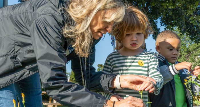 A teacher and students outside looking at flowers.