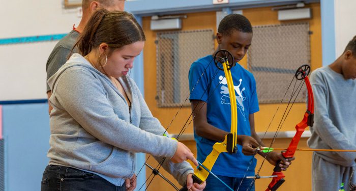 Students in a gym learning archery.
