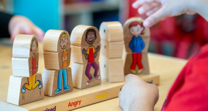 Small hands putting a puzzle together that teaches emotions.