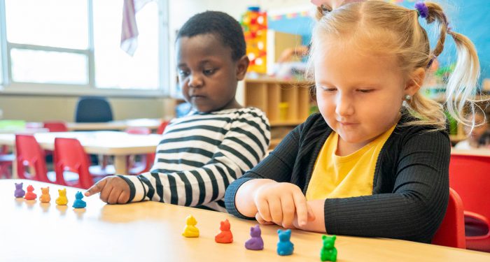 Two young students at a table counting little bears.