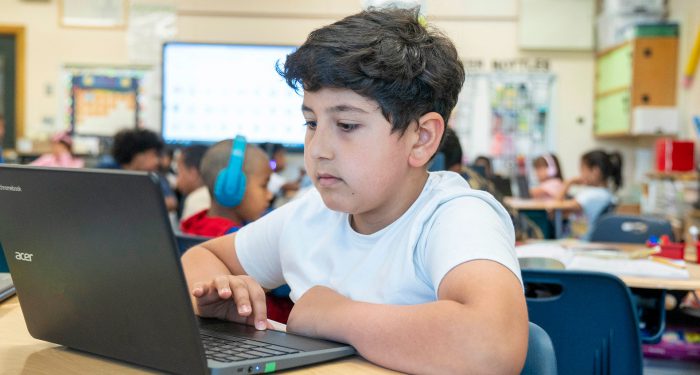 A student in a classroom using a laptop.