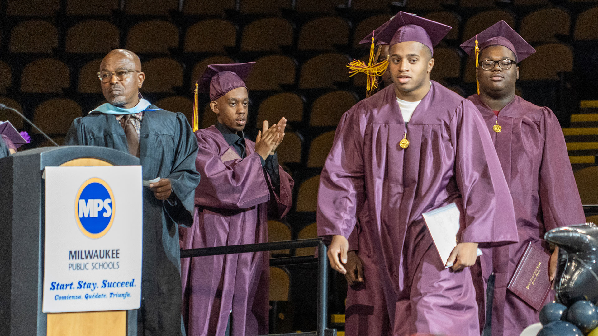 A graduate walks onto the stage to receive their diploma.