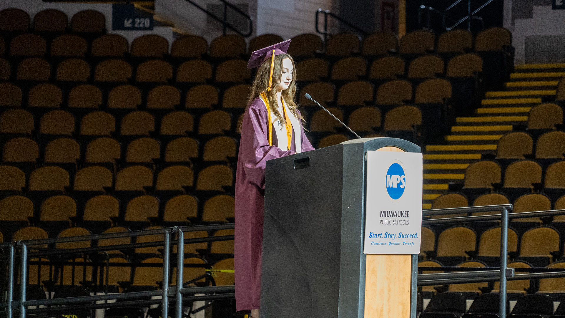 A graduate speaking at a podium.