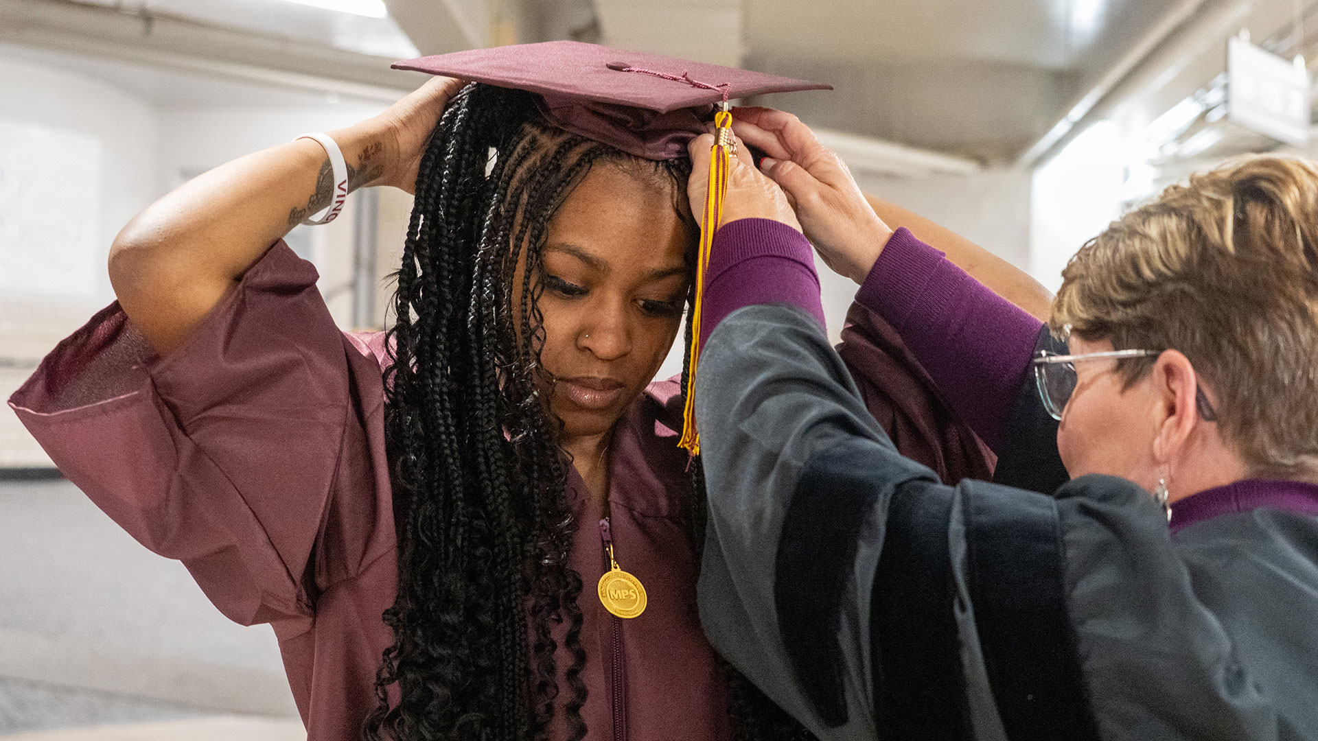 A graduate getting help putting their cap on.
