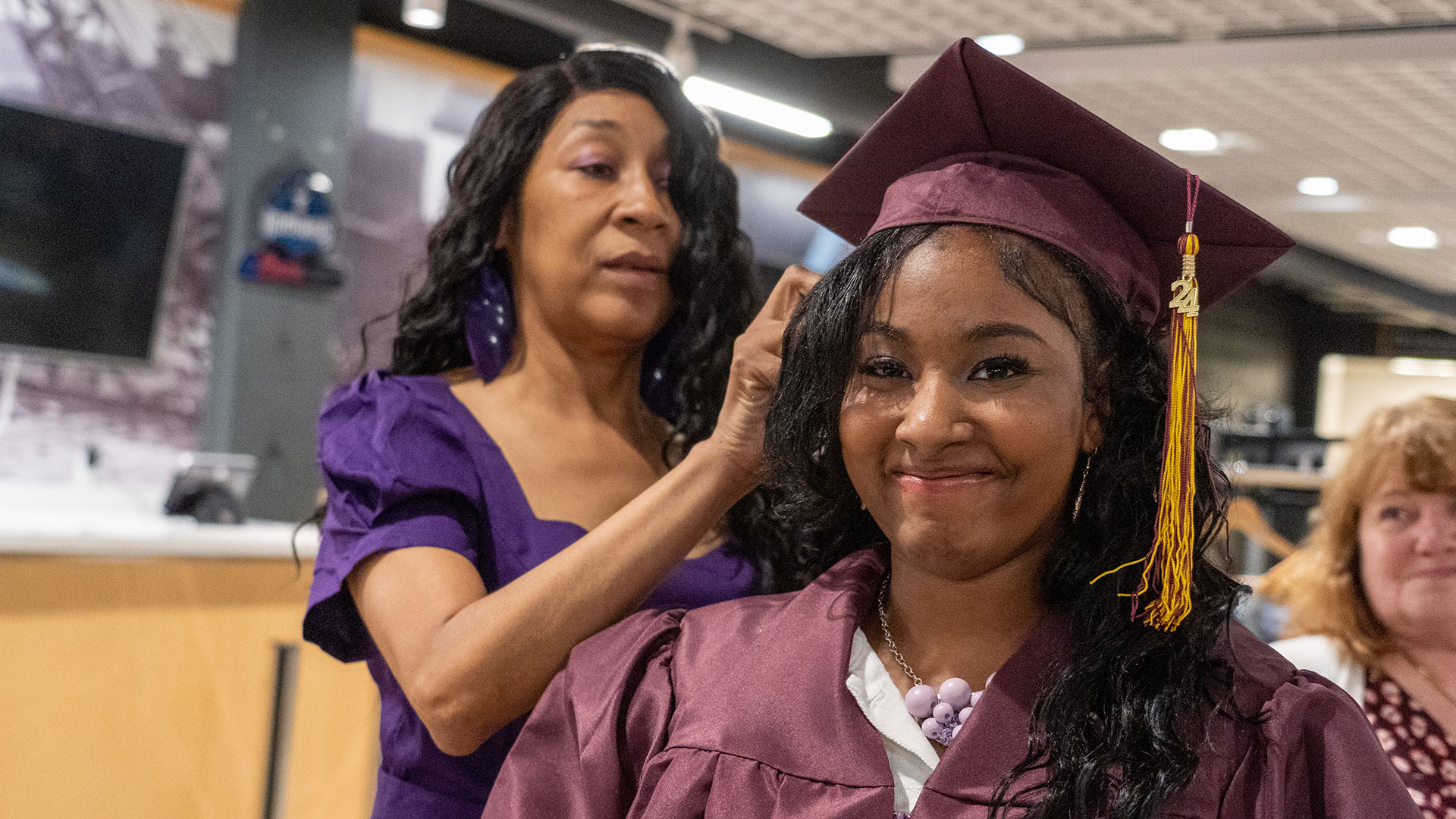 A graduate getting help putting their cap on.