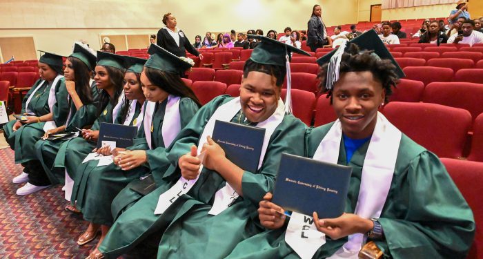 Graduates holding up their diplomas.
