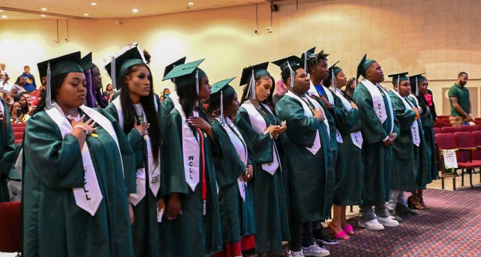 Graduates stand for the Pledge of Allegiance.