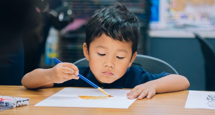 A young child at a table painting.