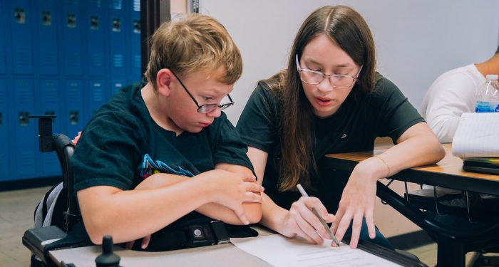 A student in a wheelchair gets help on their homework.