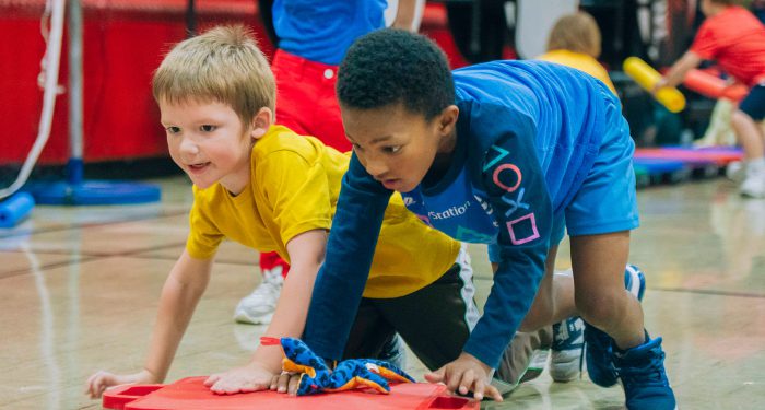 Two young students play in a gymnasium.