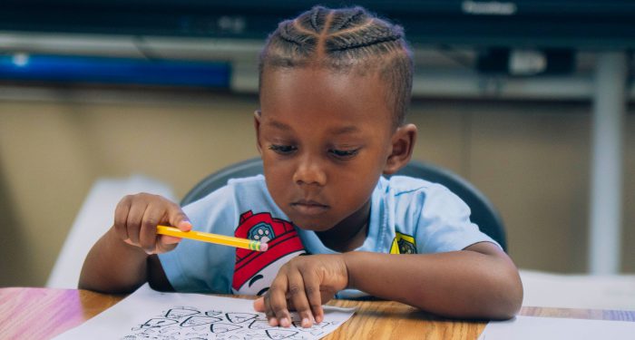A young child concentrates as they fill out a worksheet.