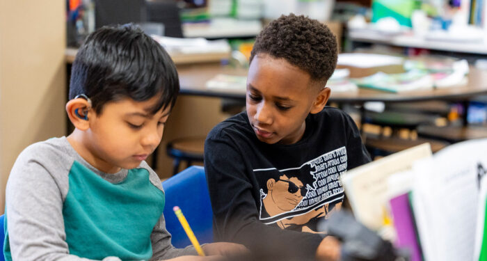 Two children in a classroom work together on an assignment.