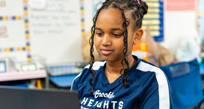 A girl in classroom looking at a computer screen.